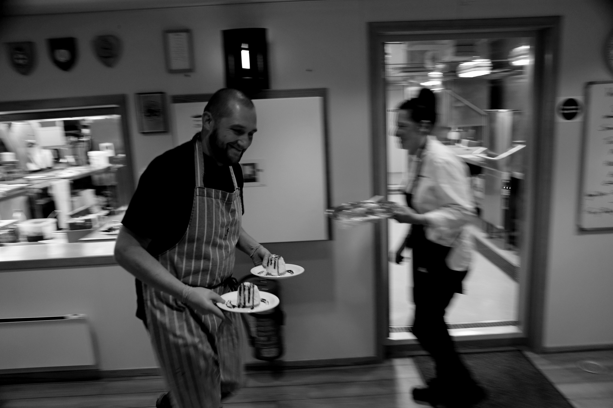 Two chefs carry plates of cake – the photo is slightly blurred