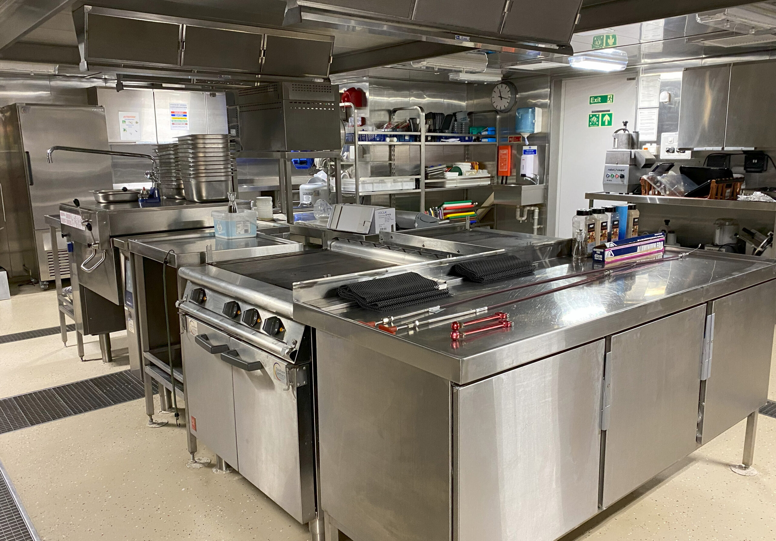 A big kitchen on a ship, full of stainless steel cookers and units