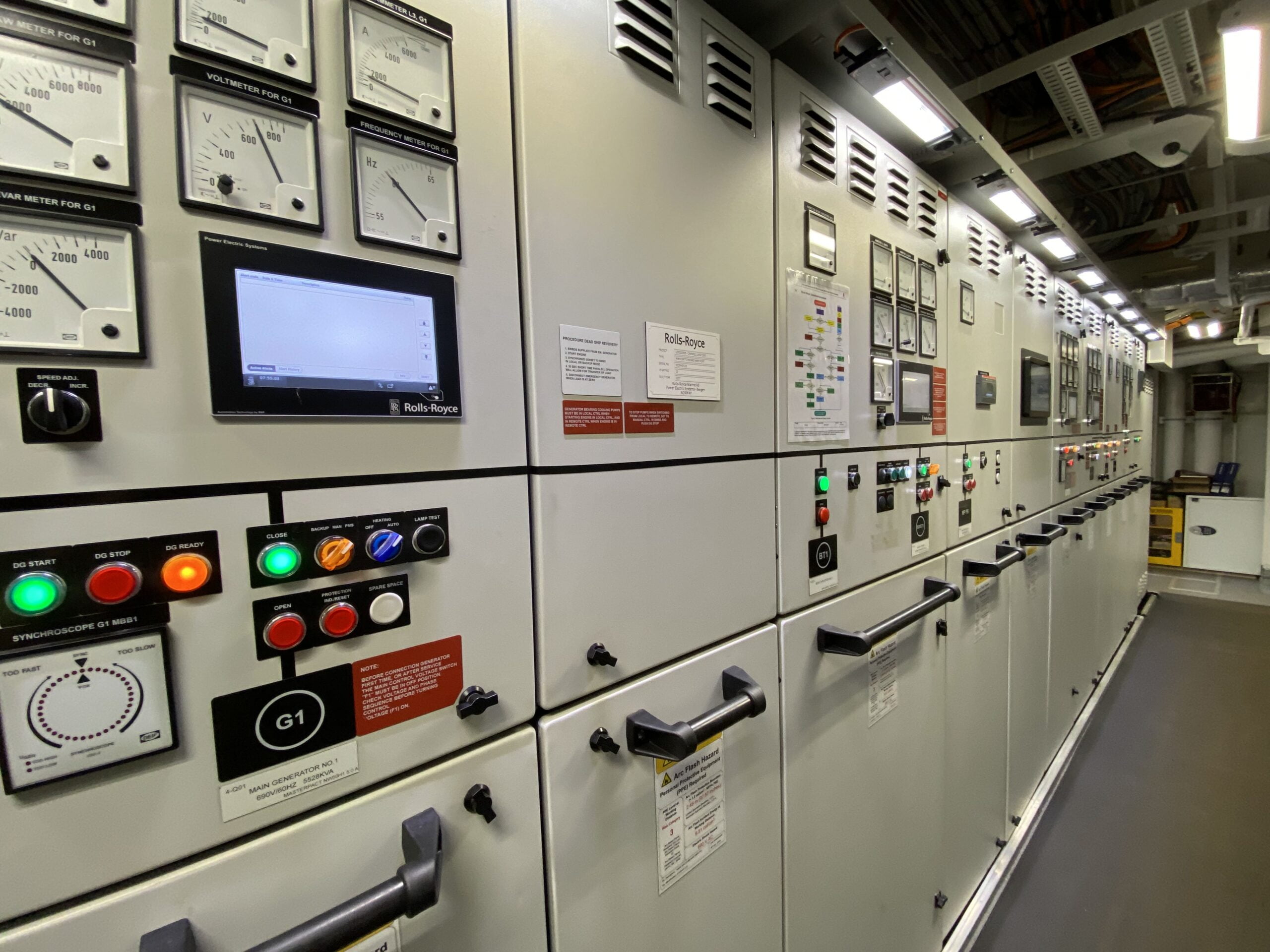 A long row of metal cabinets with various screens, lights and buttons on