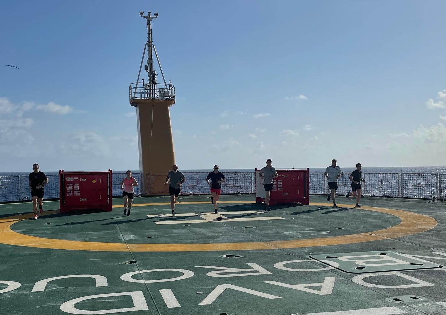 People running on the helideck of a ship