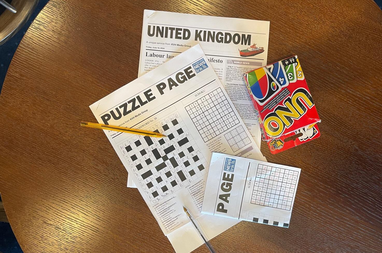 Aerial view of a newspaper puzzle page and a pack of UNO cards