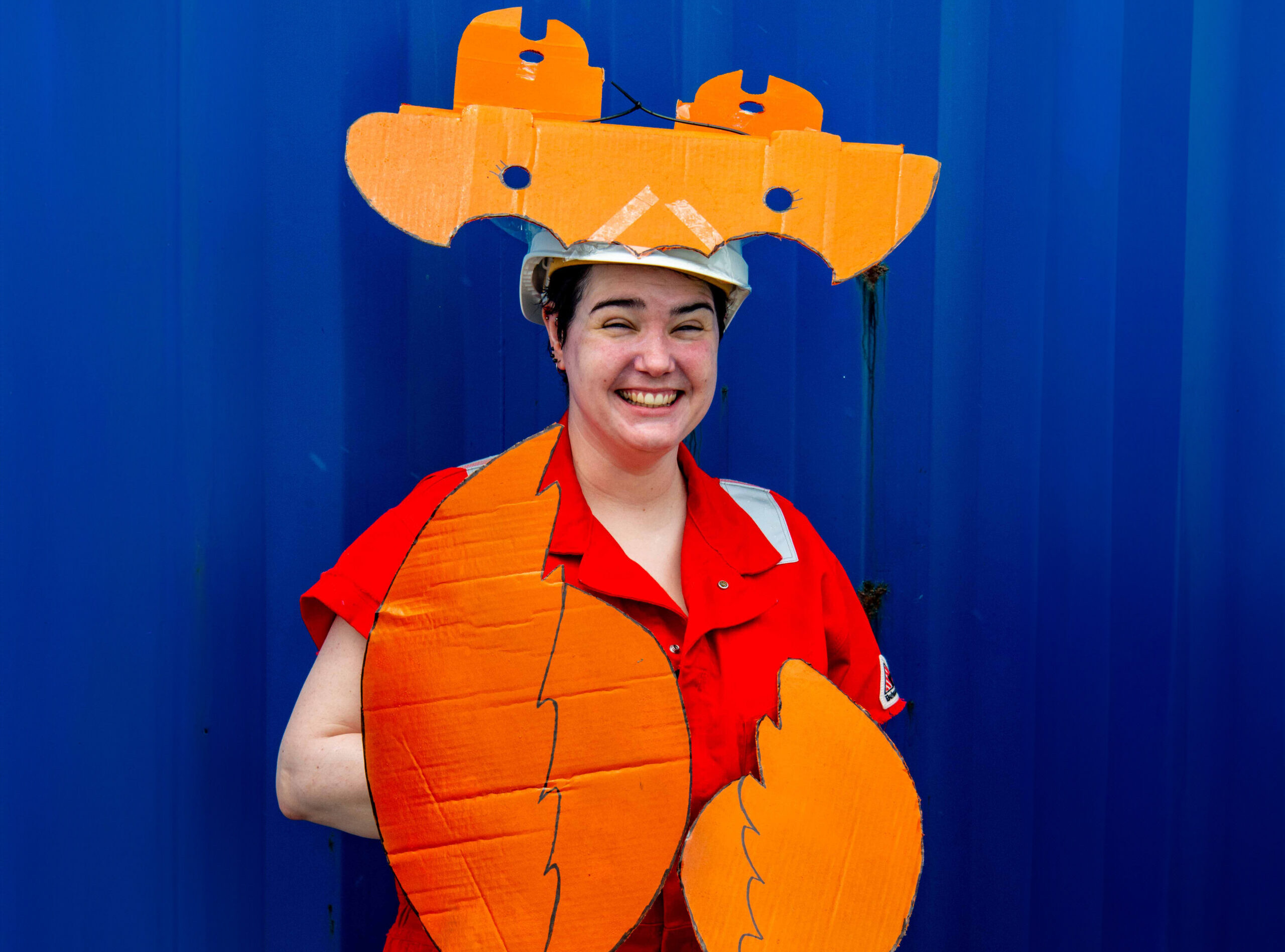 A woman dressed up as a lobster – she is wearing a red boiler suit with orange cardboard claws and head