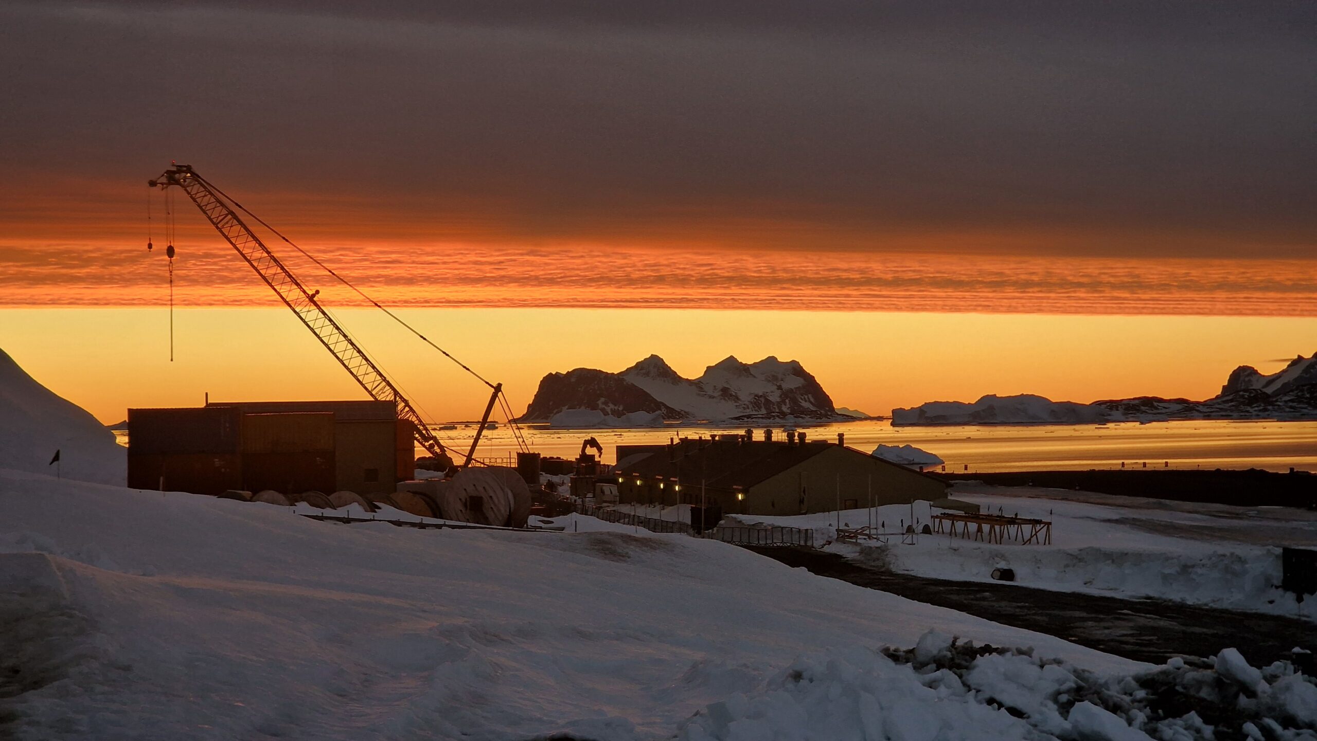 A sunset over a research village with a crane silhoutetted