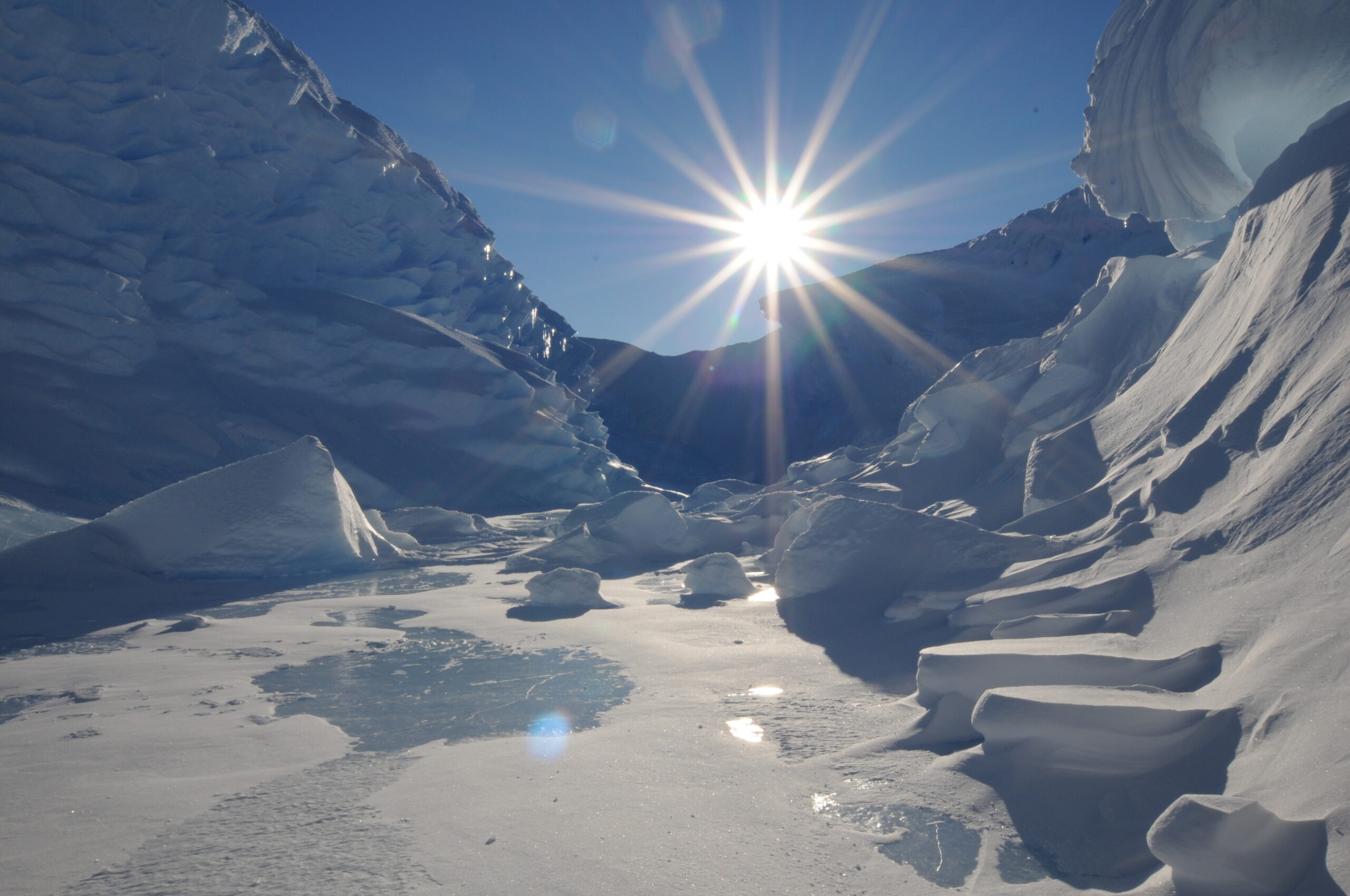 A view through a valley of ice with the sun directly in front