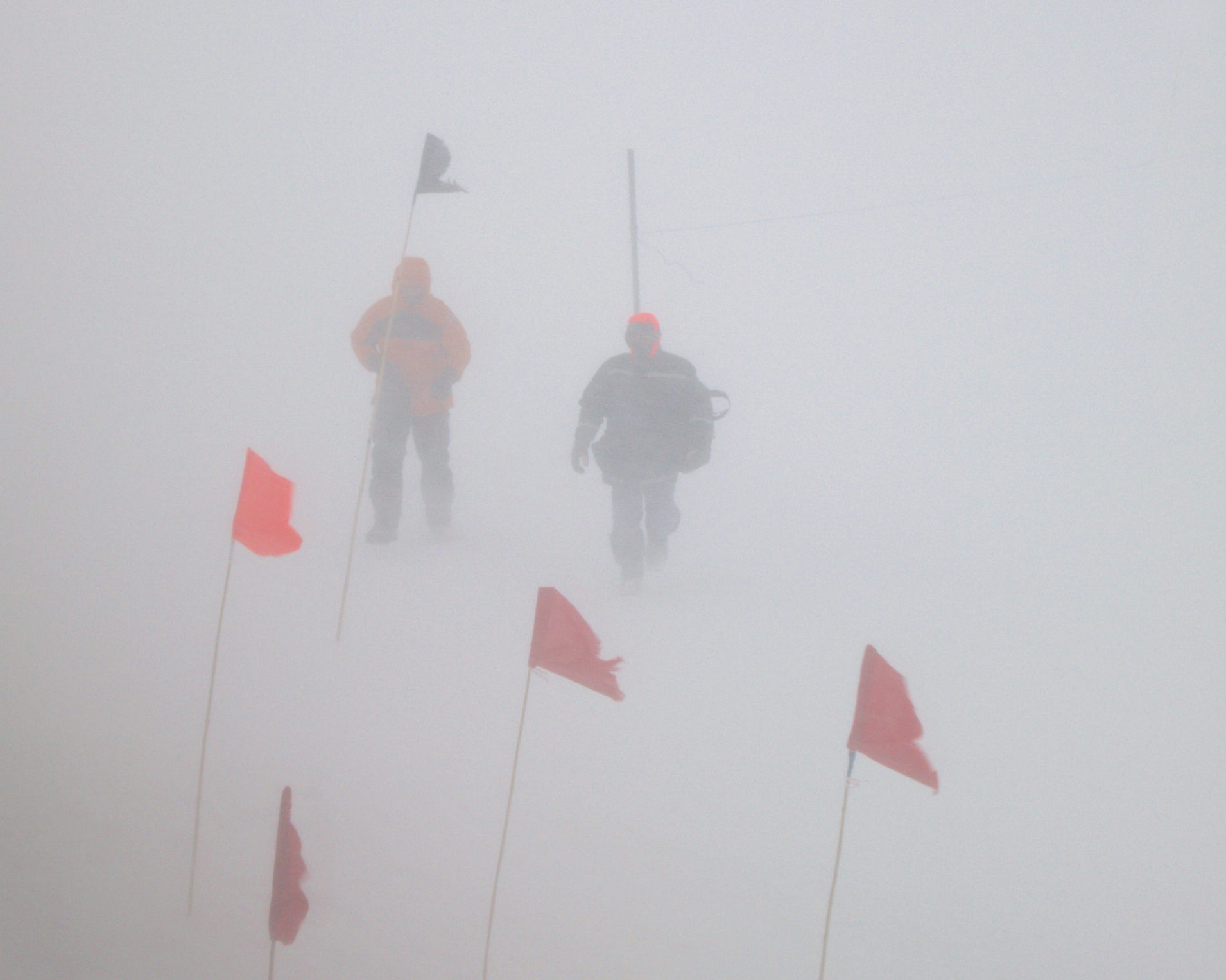 Two people barely visible in a snowstorm