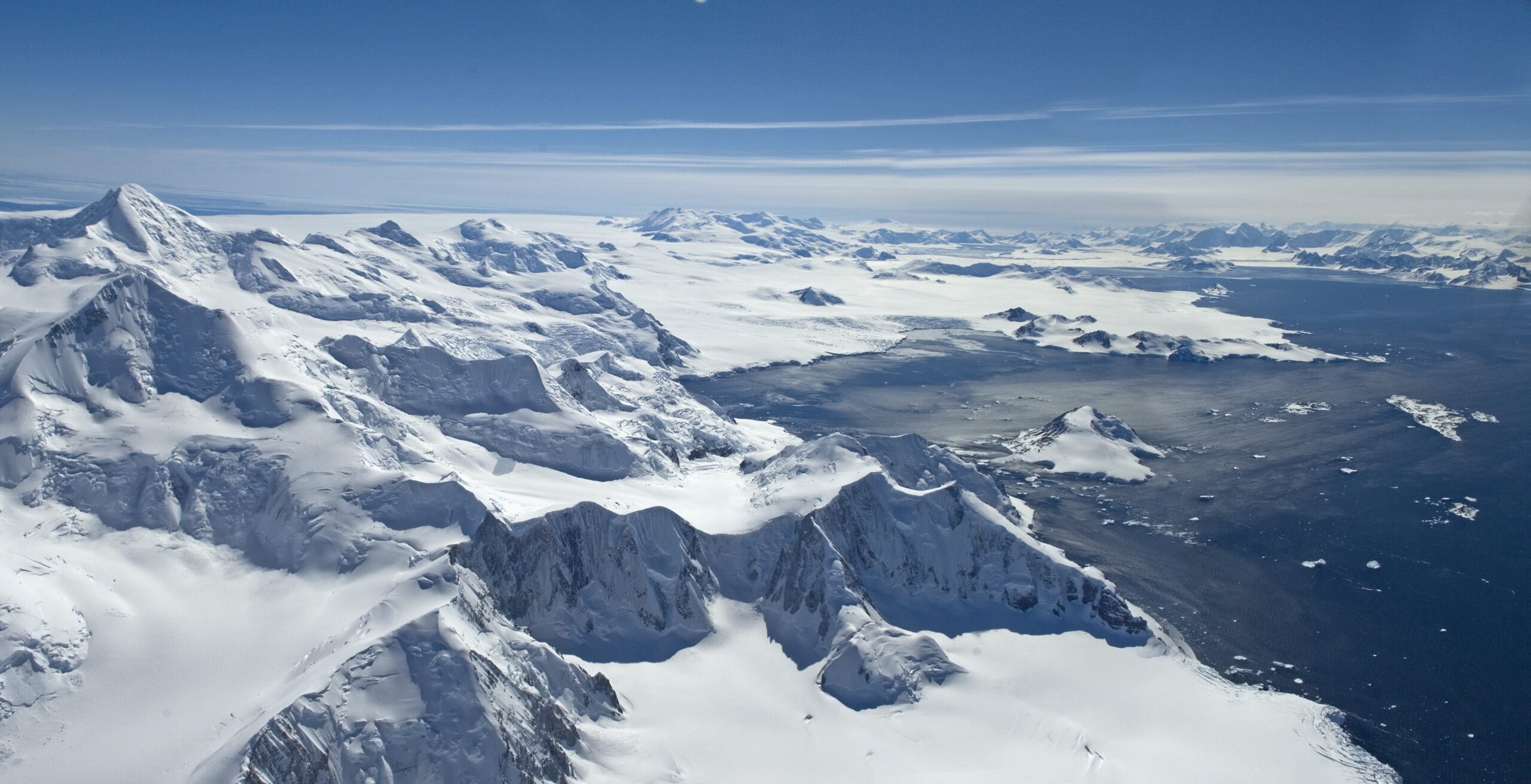 An aerial view of snowy mountains and a sweeping bay