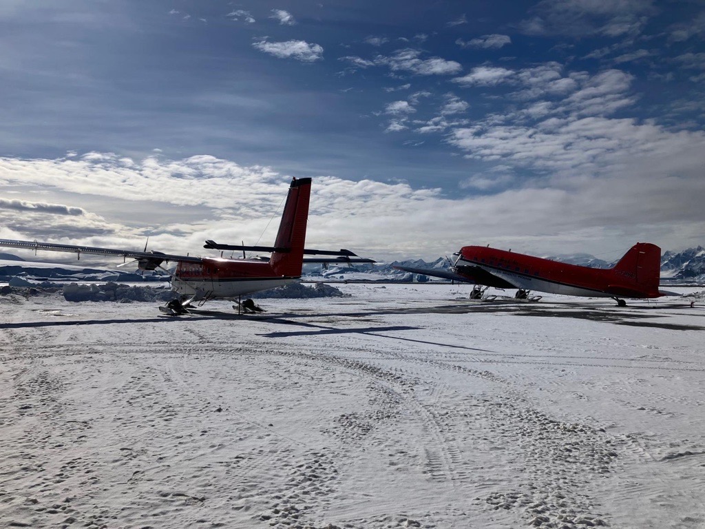 Two red and white planes sat on ice