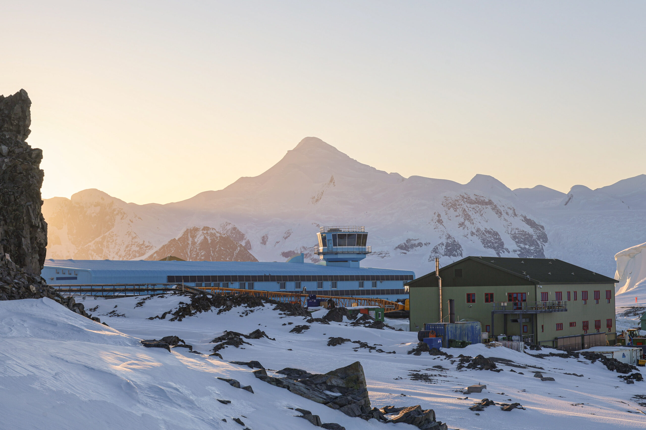 Rothera Research Station at sunset - a bright blue building sits in front of a glowing mountain
