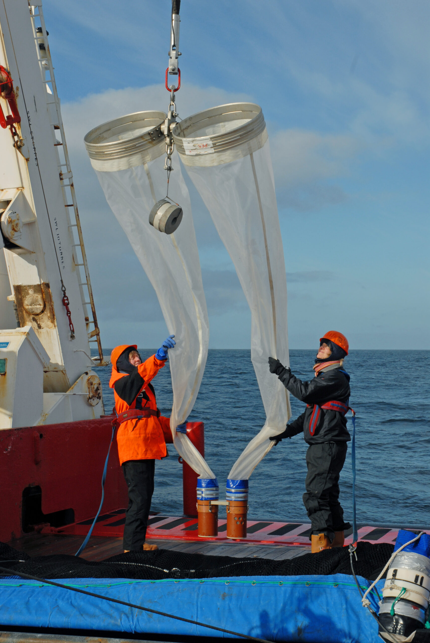 Two people on a ship holding a giant net