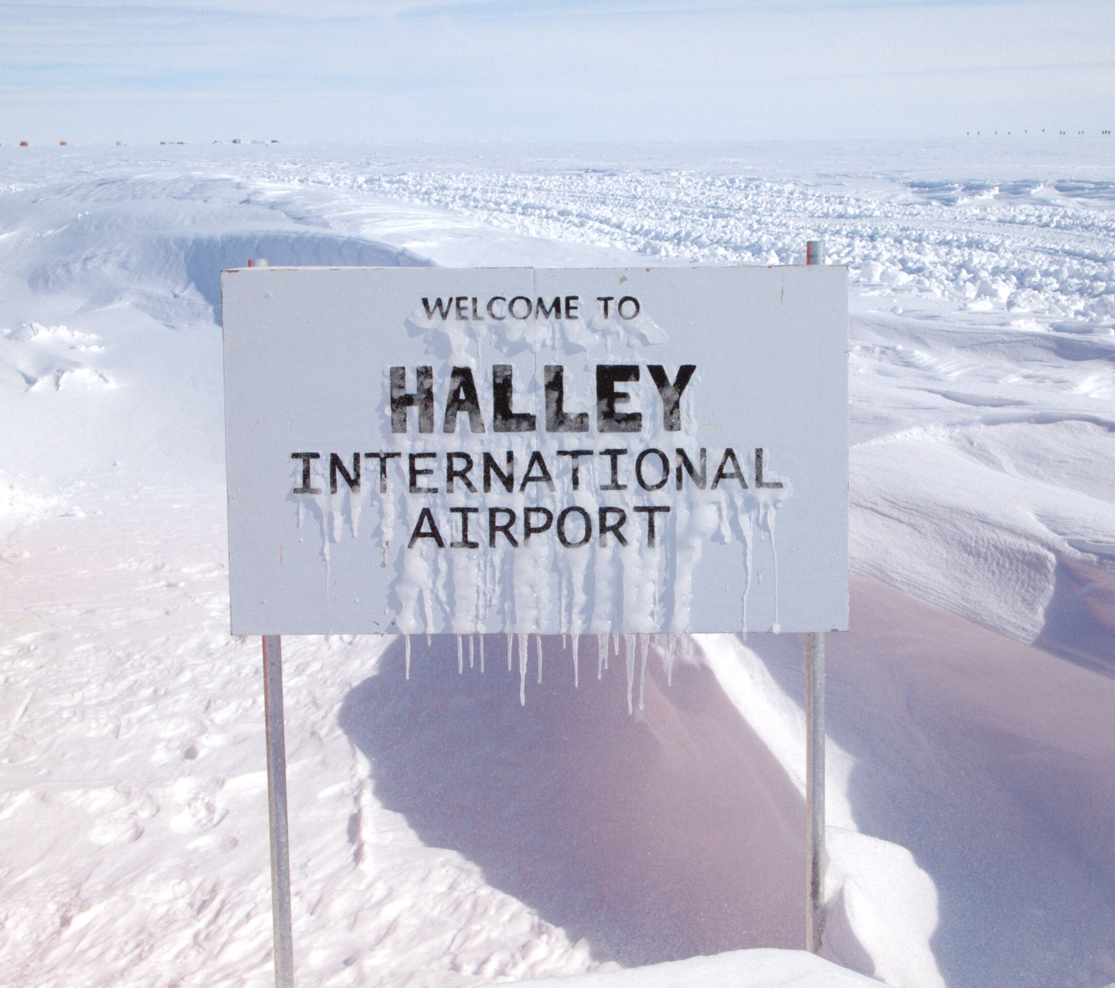 A sign that reads Welcome to Halley International Airport, covered in snow and ice