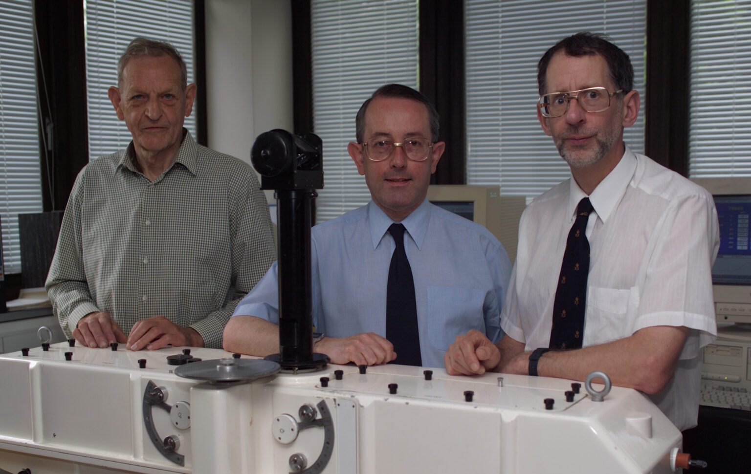 Three men standing around a science instrument