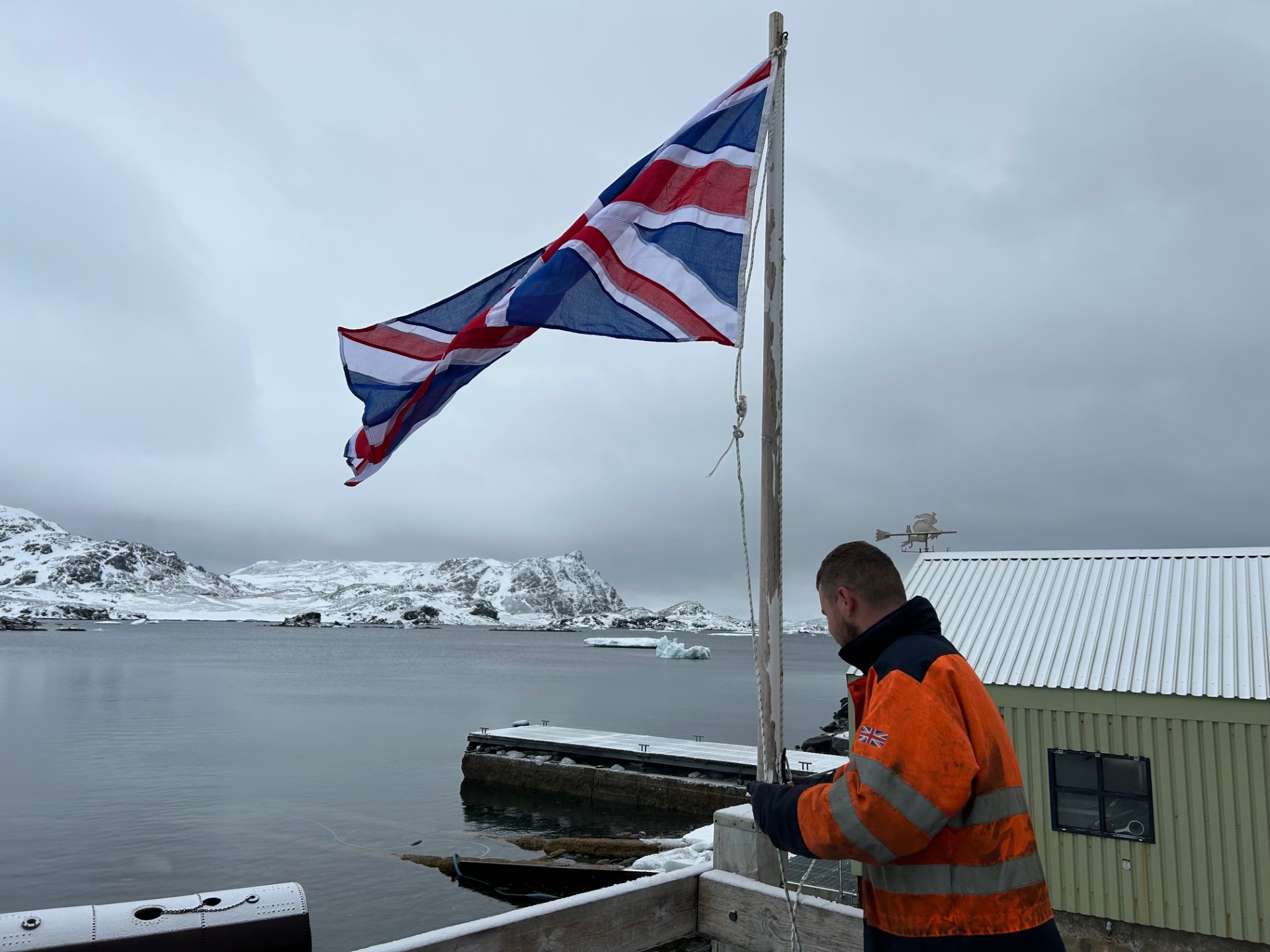 A man in an orange high-vis jacket raises a Union Jack