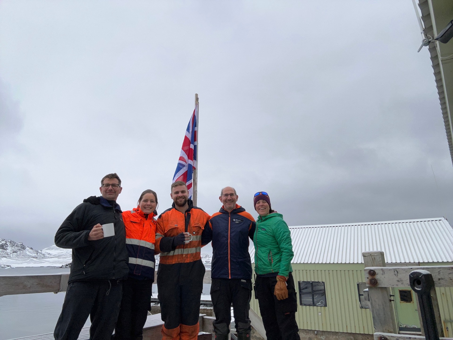 Five people stood together in cold weather clothes in front of the Union Jack