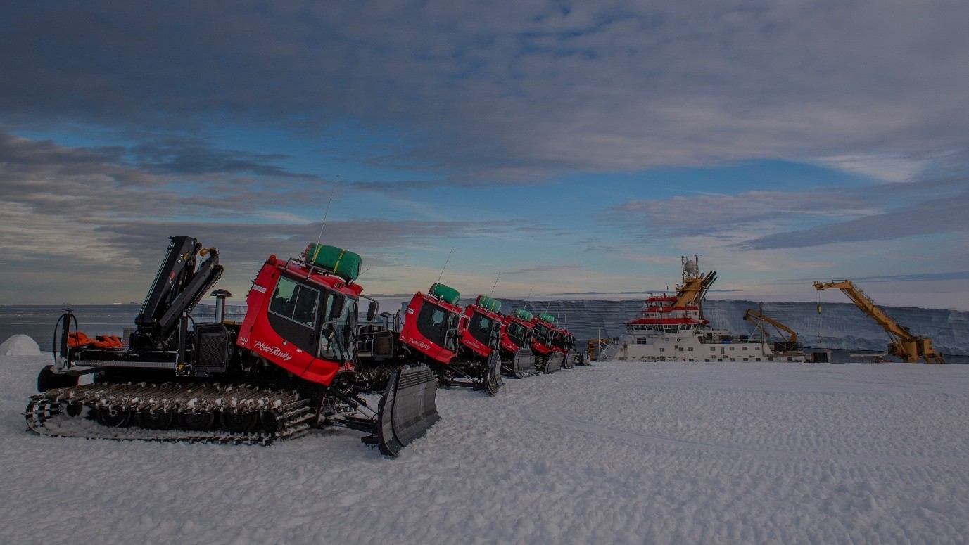 Tractors with scoops lined up along an ice shelf