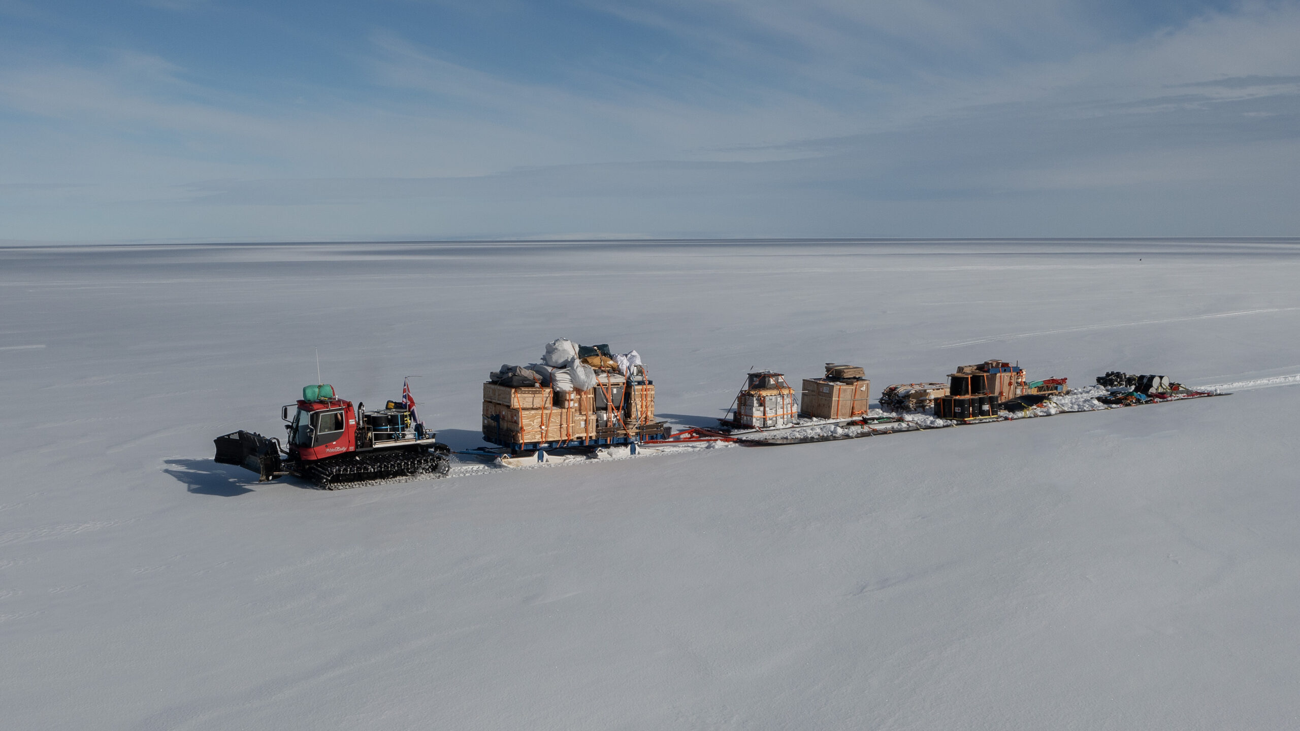 A tractor train traverse of vehicles carrying cargo in a snowy landscape