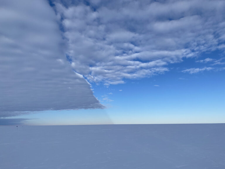 A large flat cloud dominates half the sky in a snowy landscape